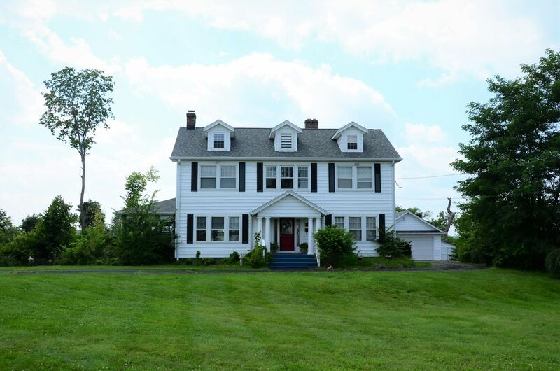 White center-hall colonial with red front door and a detached garage beside it