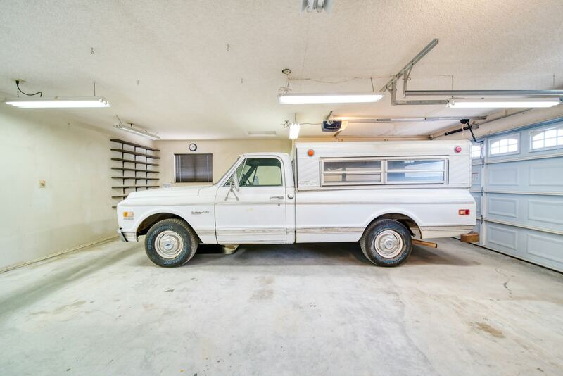Garage interior showing ceiling-mounted opener, rail and overhead door tracks beside a pickup