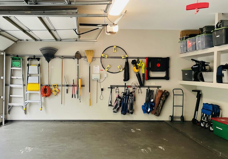 Open overhead garage door on its tracks with the opener above a tidy tool wall