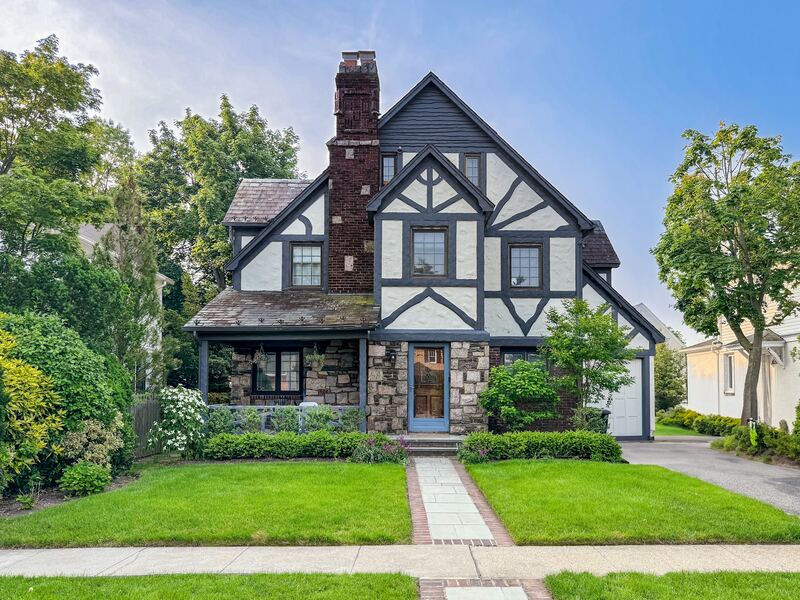 Tudor Revival home with stone entry, half-timbered gables, and a side driveway garage