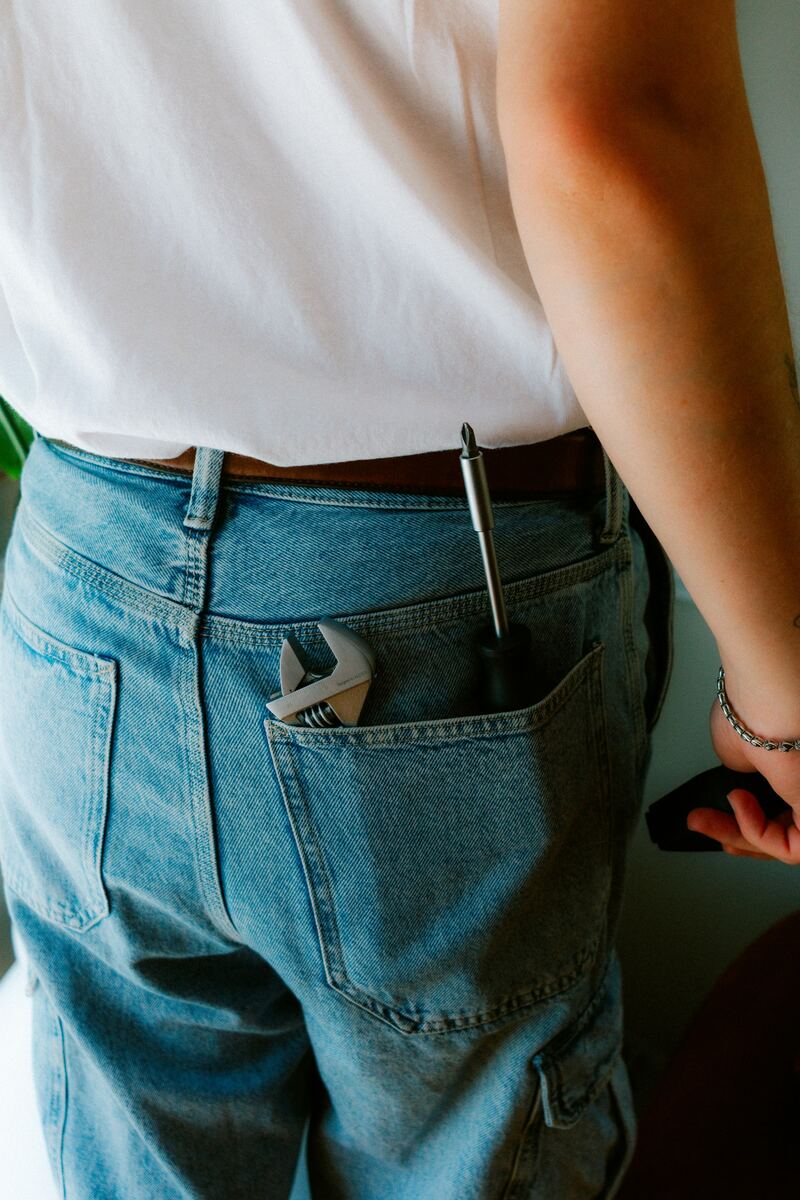 Adjustable wrench and screwdriver tucked into the back pocket of work jeans